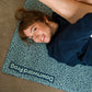Person lying down on printed yoga mat, with whirly pattern
