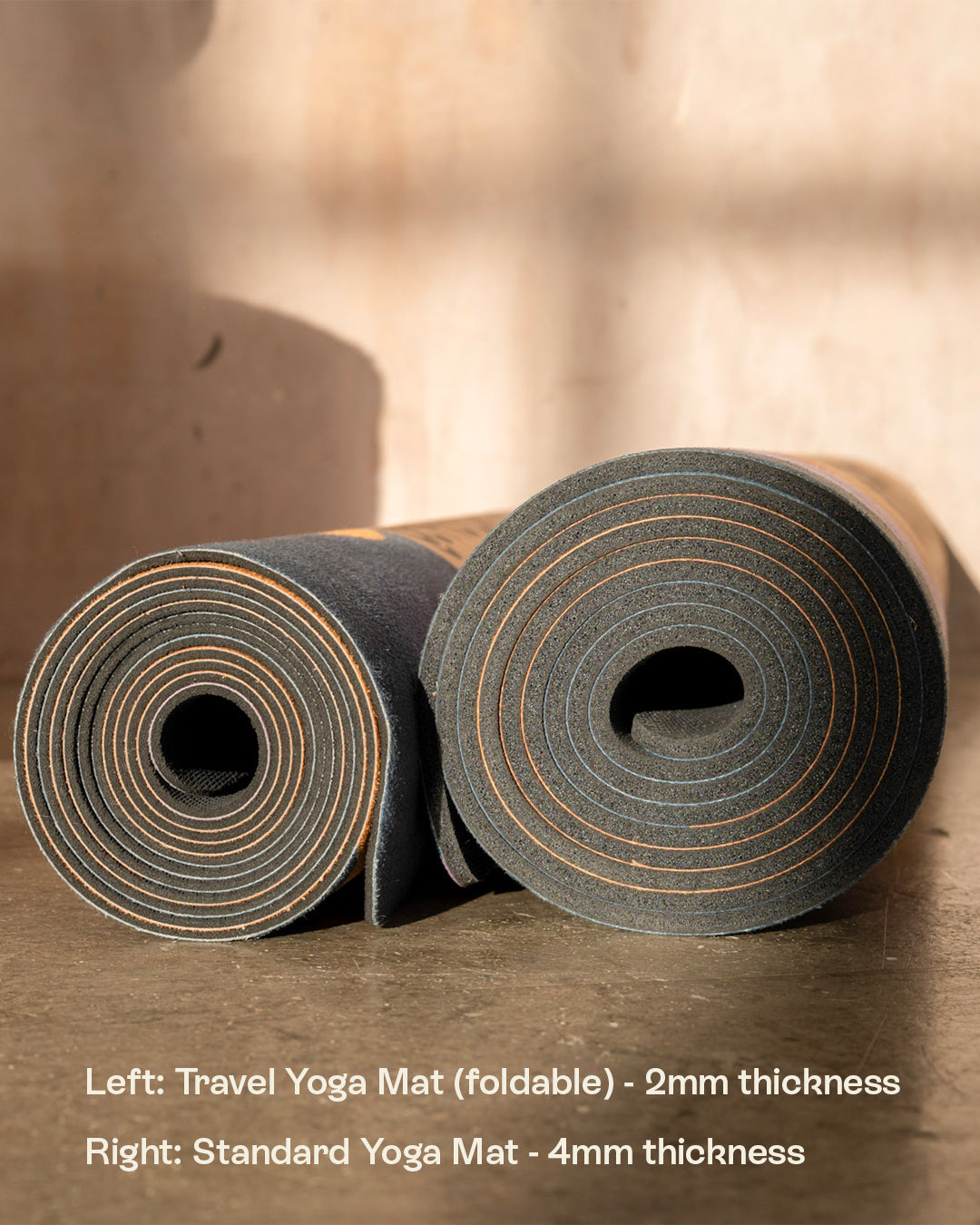 Two yoga mats, one travel mat and one standard mat, on a wooden surface with text indicating thickness.