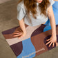 Person stretching on a colorful yoga mat with Downward Frog branding