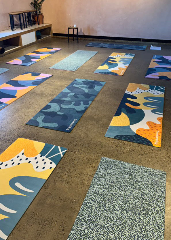 Colorful yoga mats arranged on a concrete floor in a yoga studio, available to hire